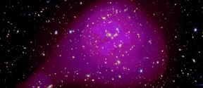 A galaxy cluster with numerous stars and galaxies scattered against a dark background, with a large magenta cloud in the centre.
