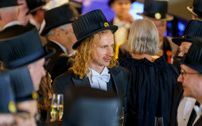 A man with a doctor's hat on celebrating his promotion as a doctor with other doctors